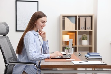 Photo of Copywriter using laptop at wooden table indoors