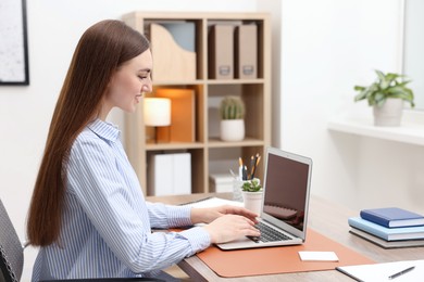 Photo of Copywriter using laptop at wooden table indoors