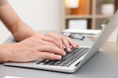 Photo of Copywriter using laptop at wooden table indoors, closeup