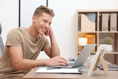 Photo of Copywriter using laptop at wooden table indoors
