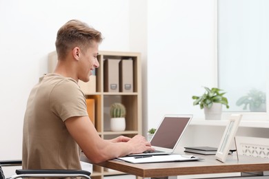 Photo of Copywriter using laptop at wooden table indoors