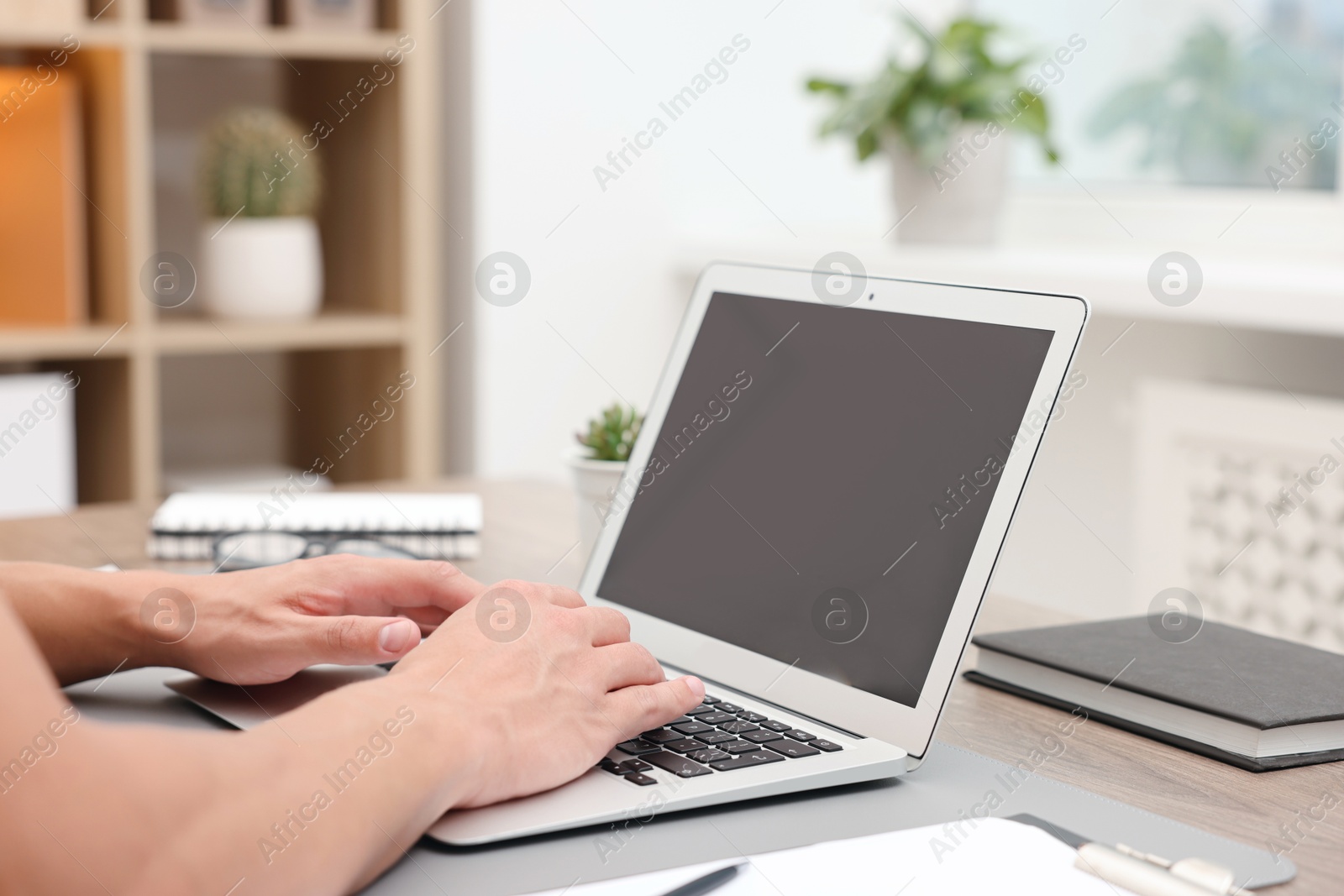Photo of Copywriter using laptop at wooden table indoors, closeup