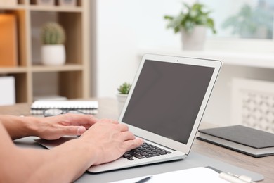 Photo of Copywriter using laptop at wooden table indoors, closeup