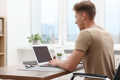 Photo of Copywriter using laptop at wooden table indoors