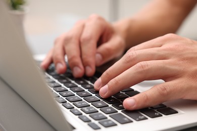 Photo of Copywriter using laptop at wooden table indoors, closeup