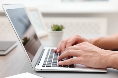 Photo of Copywriter using laptop at wooden table indoors, closeup
