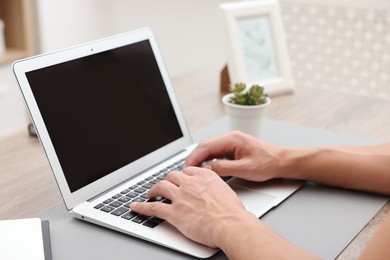 Photo of Copywriter using laptop at wooden table indoors, closeup