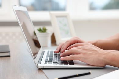 Photo of Copywriter using laptop at wooden table indoors, closeup