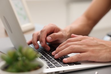 Photo of Copywriter using laptop at wooden table indoors, closeup