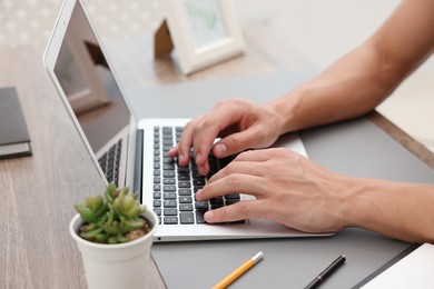 Photo of Copywriter using laptop at wooden table indoors, closeup