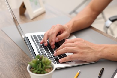 Photo of Copywriter using laptop at wooden table indoors, closeup