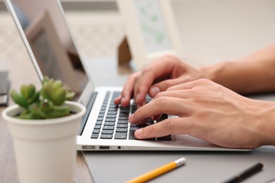 Photo of Copywriter using laptop at wooden table indoors, closeup