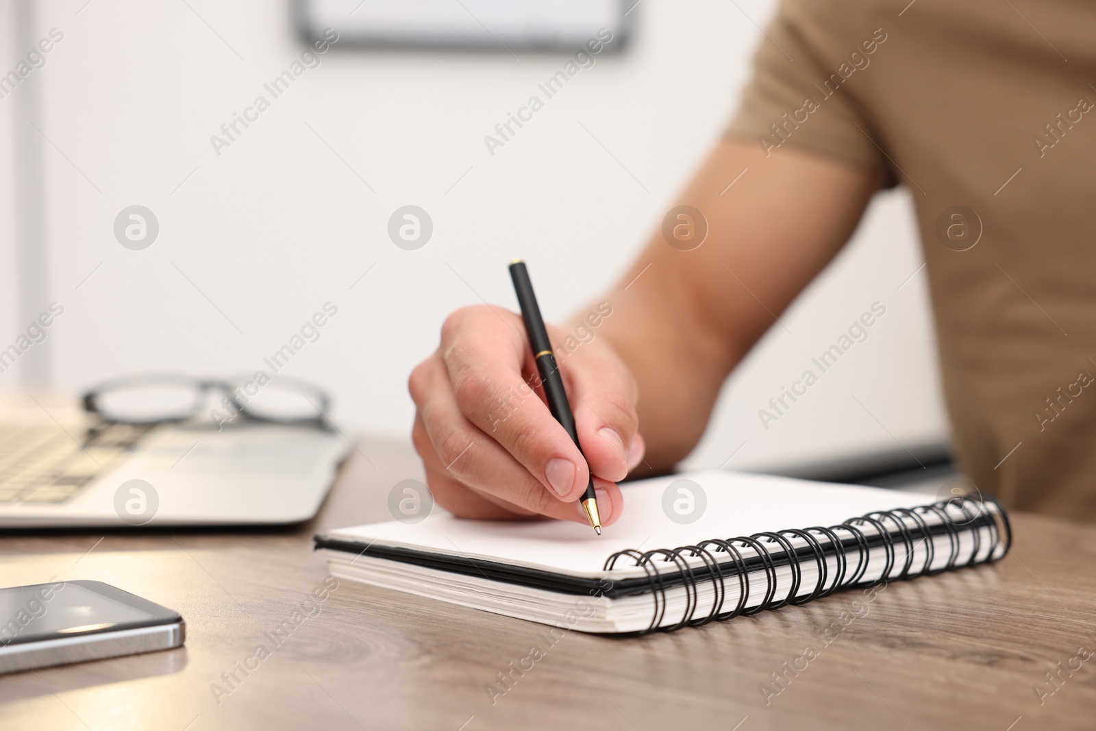 Copywriter writing in notebook at wooden table indoors, closeup Photo of Copywriter writing in notebook at wooden table indoors, closeup