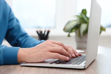 Photo of Copywriter using laptop at wooden table indoors, closeup