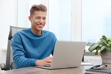Photo of Copywriter using laptop at wooden table indoors