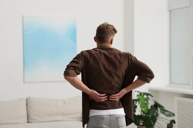 Photo of Man suffering from pain at home, back view