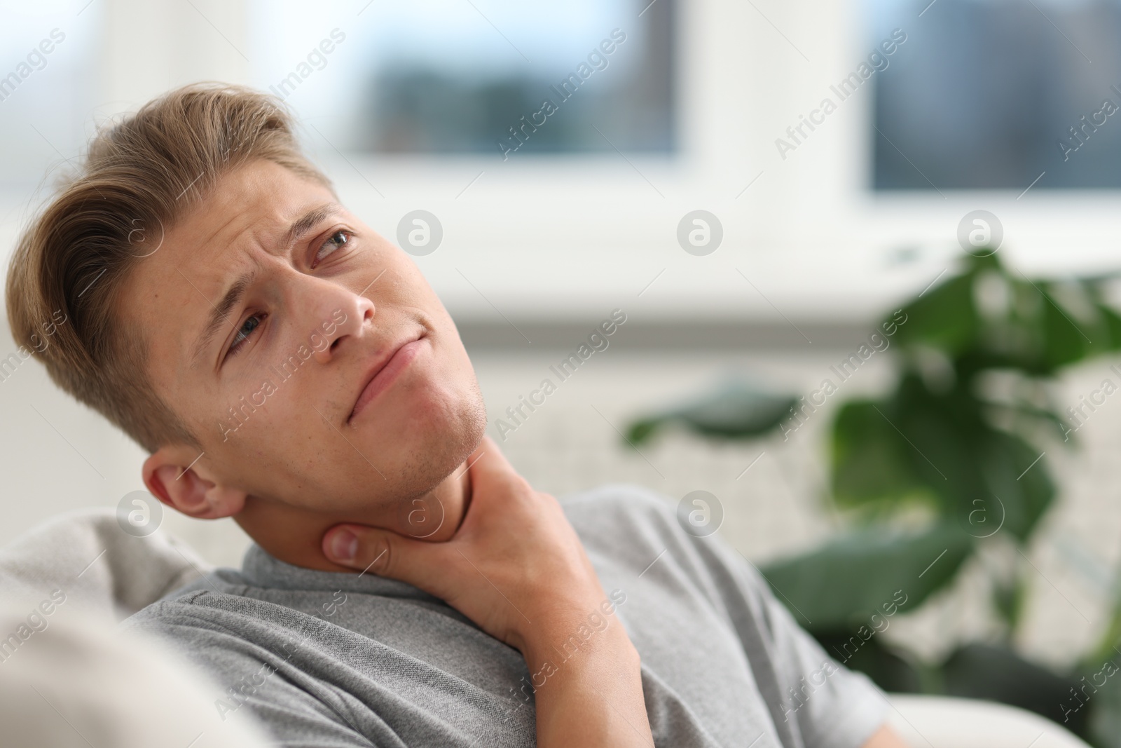 Photo of Young man suffering from sore throat at home. Space for text