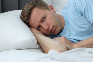 Photo of Portrait of sad man lying on bed at home. Depression