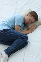 Photo of Sad man trying to sleep on bed, above view. Depression