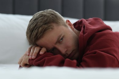 Photo of Sad thoughtful man lying on bed. Depression
