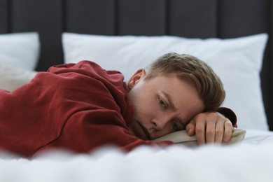 Photo of Sad man lying on bed at home. Depression