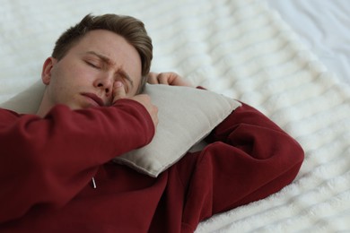 Photo of Sad man with pillow lying on bed. Depression