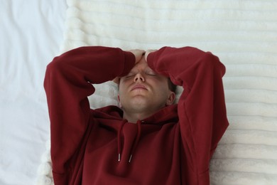 Photo of Sad tired man lying on bed, above view. Depression