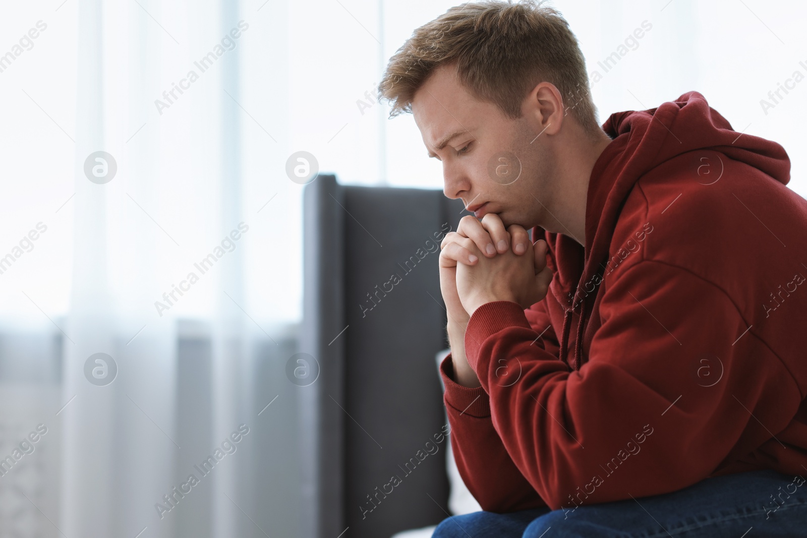 Sad thoughtful man sitting on bed at home. Space for text Photo of Sad thoughtful man sitting on bed at home. Space for text