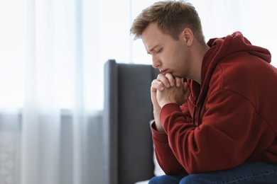 Photo of Sad thoughtful man sitting on bed at home. Space for text