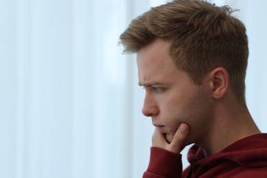 Photo of Sad thoughtful man on blurred light background, closeup. Space for text