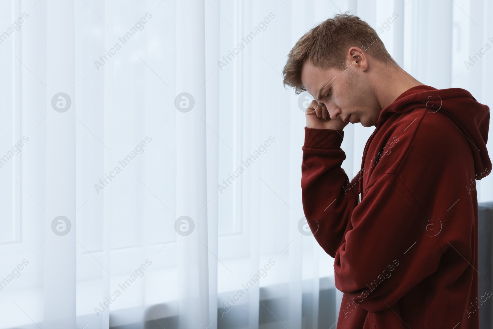 Sad thoughtful man near window at home. Space for text Photo of Sad thoughtful man near window at home. Space for text