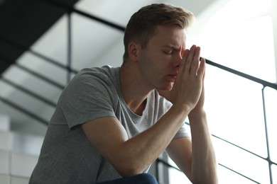 Photo of Sad tired man sitting on stairs indoors. Depression