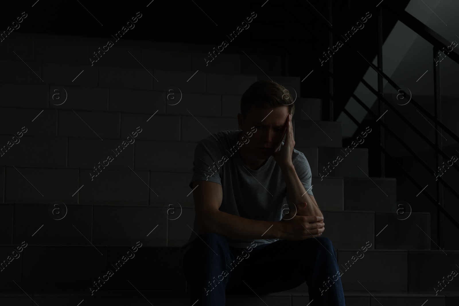 Sad man sitting on stairs in darkness. Depression Photo of Sad man sitting on stairs in darkness. Depression