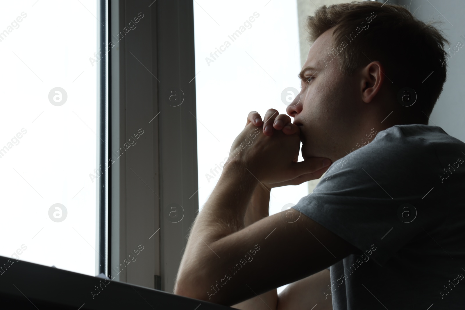 Sad thoughtful man looking at window indoors, low angle view with space for text. Depression Photo of Sad thoughtful man looking at window indoors, low angle view with space for text. Depression
