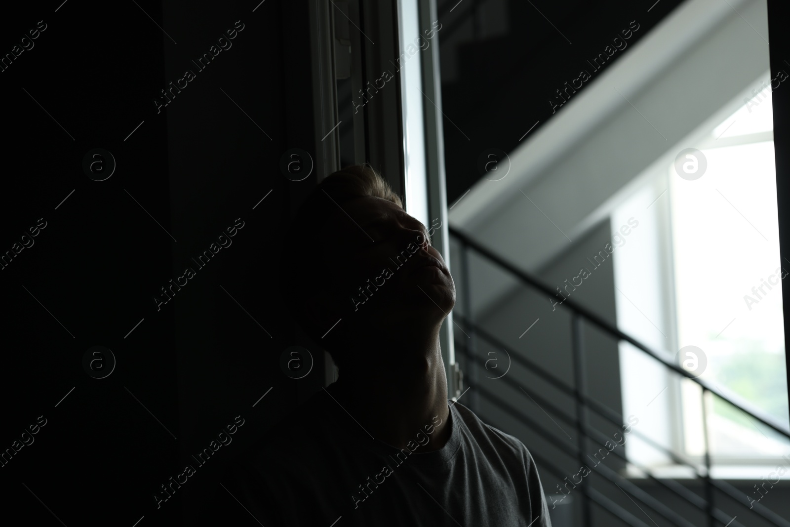 Sadness and depression. Tired man in dark room with open door and window with daylight Photo of Sadness and depression. Tired man in dark room with open door and window with daylight