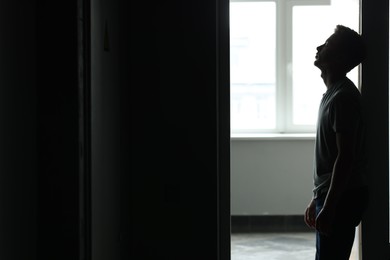 Photo of Sadness and depression. Tired man in dark room with open door against window with daylight. Space for text