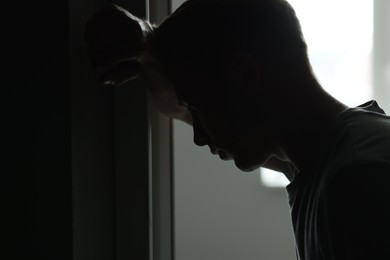 Photo of Sadness and depression. Silhouette of man in darkness against daylight