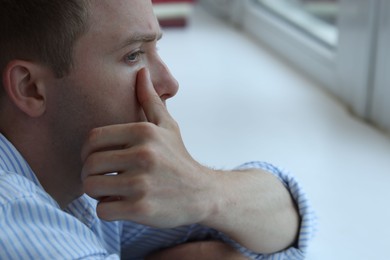 Photo of Sad man crying alone indoors, closeup. Depression and anxiety