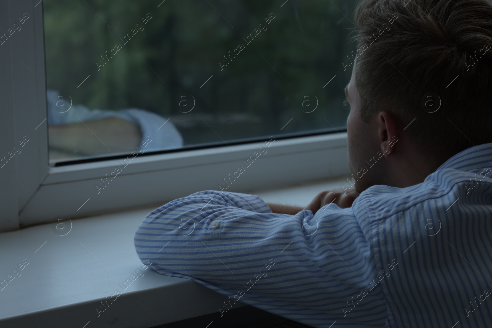 Sad lonely man looking at window indoors Photo of Sad lonely man looking at window indoors