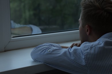 Photo of Sad lonely man looking at window indoors