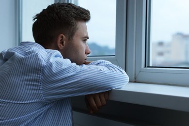 Photo of Sad lonely man looking at window indoors