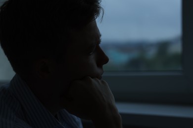 Photo of Sad tired man in darkness at home, space for text. Depression