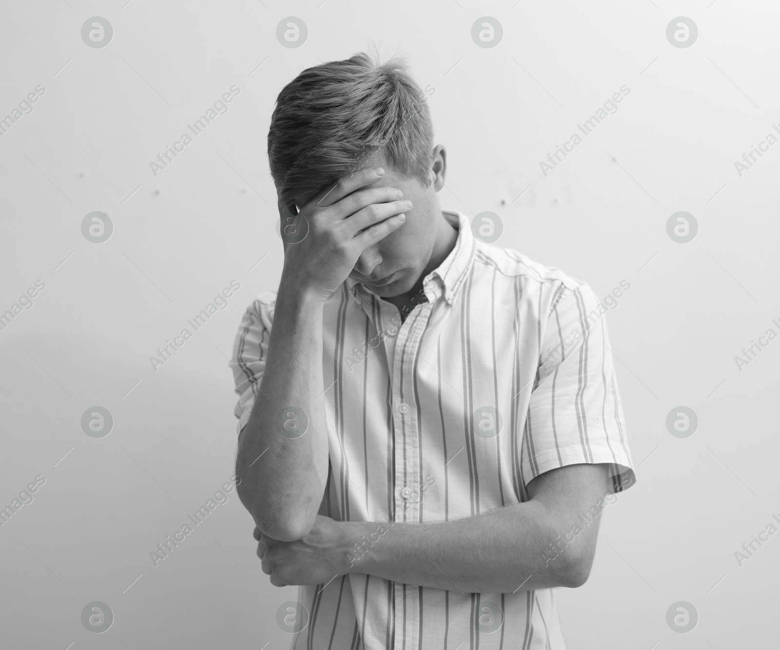 Sad tired man covering face with hand on grey background. Black and white effect Photo of Sad tired man covering face with hand on grey background. Black and white effect