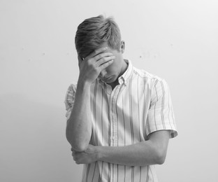 Photo of Sad tired man covering face with hand on grey background. Black and white effect