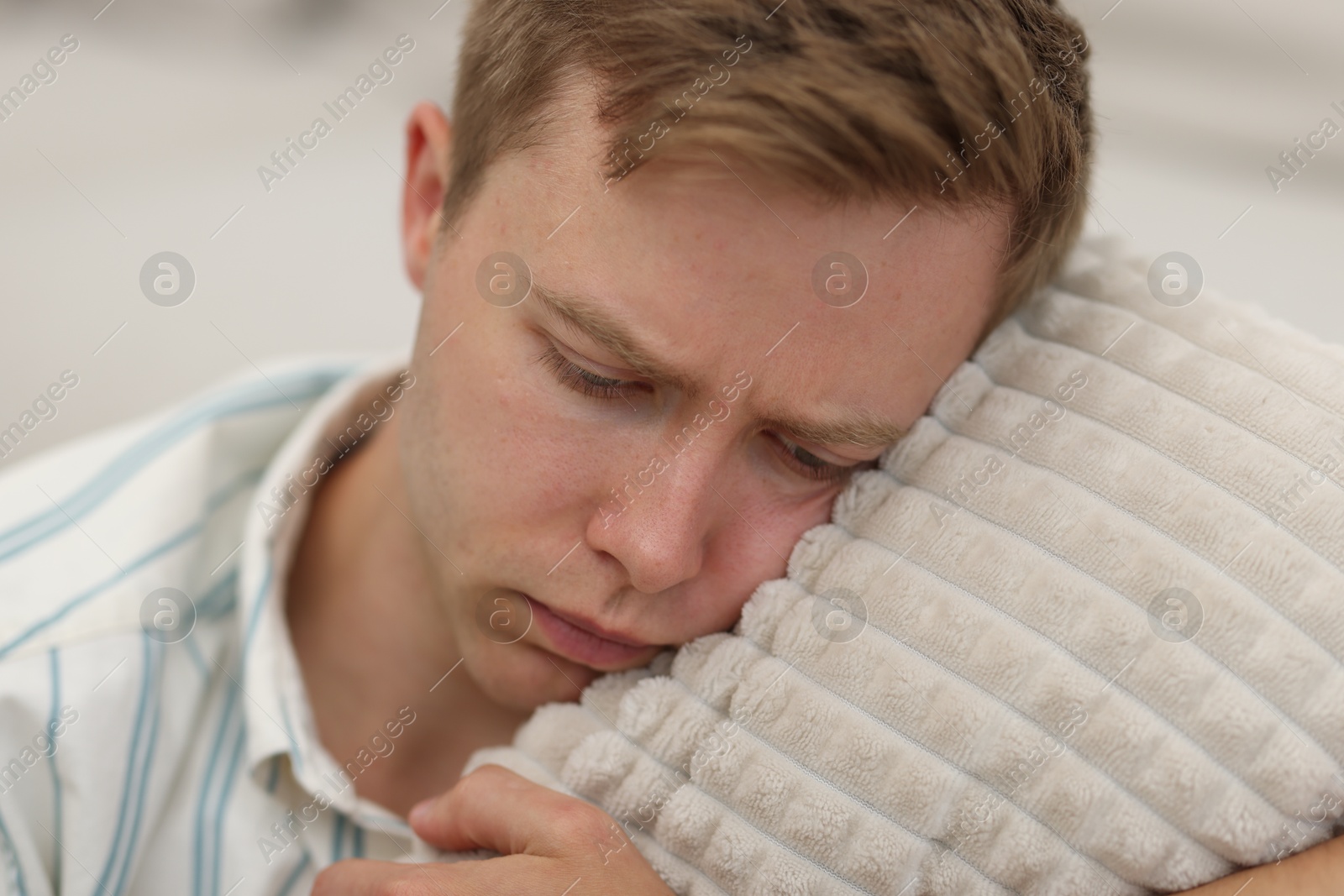 Sad tired man with pillow on blurred background Photo of Sad tired man with pillow on blurred background