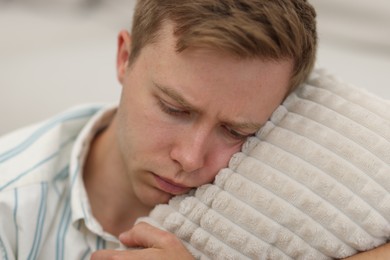 Photo of Sad tired man with pillow on blurred background