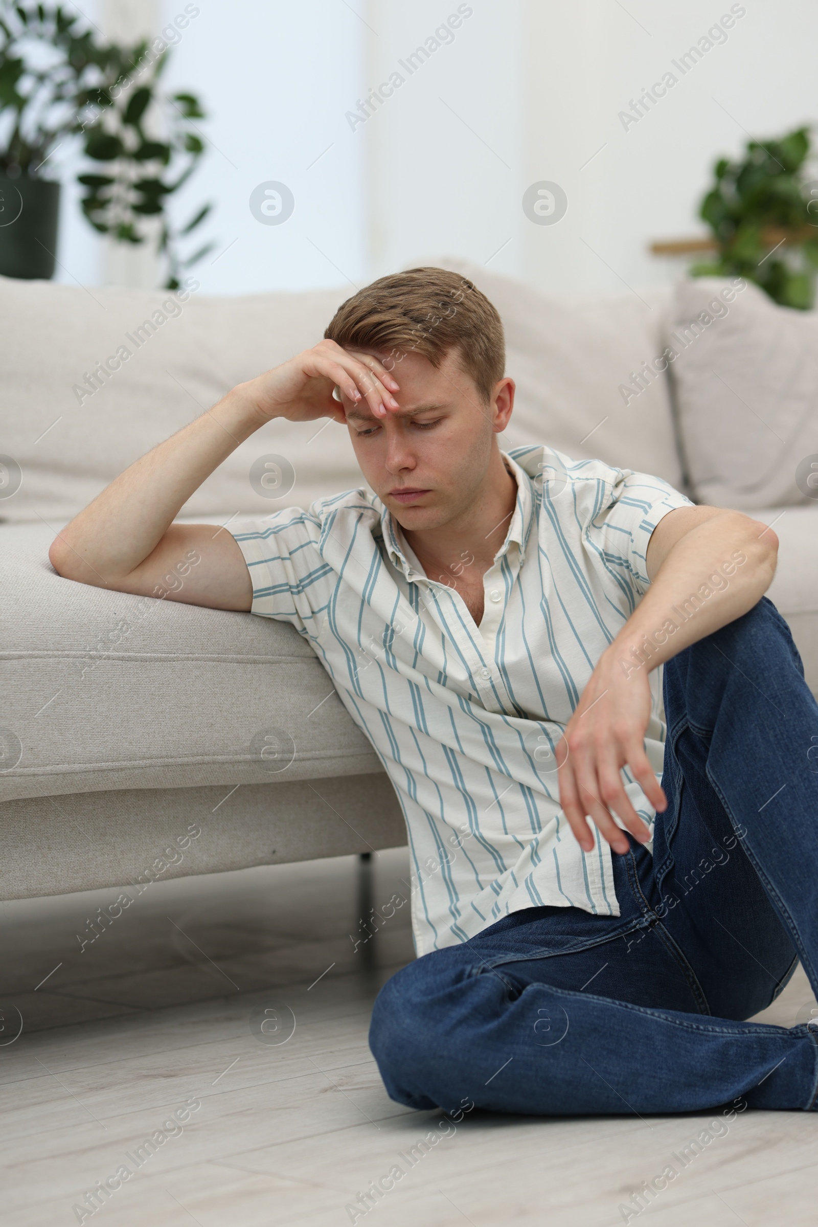 Sad thoughtful man leaning on sofa at home Photo of Sad thoughtful man leaning on sofa at home