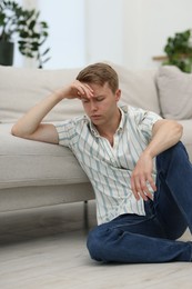 Photo of Sad thoughtful man leaning on sofa at home