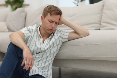 Photo of Sad thoughtful man leaning on sofa at home
