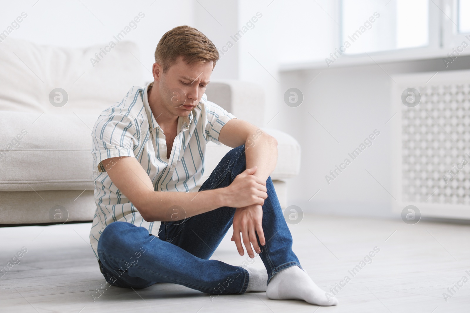 Sad thoughtful man sitting on floor at home Photo of Sad thoughtful man sitting on floor at home